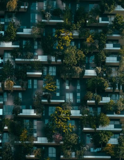 A vertical shot of a futuristic building with natural decorations on its facade